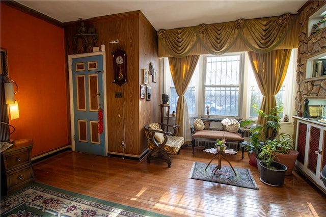 sitting room featuring wood-type flooring, ornamental molding, and wooden walls