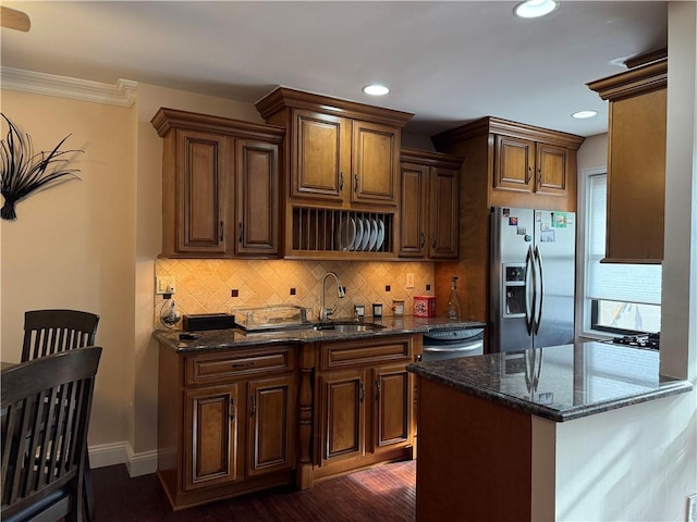 kitchen featuring backsplash, a sink, stainless steel fridge with ice dispenser, and dark stone countertops