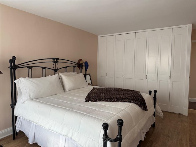 bedroom featuring dark wood-style flooring, a closet, and baseboards