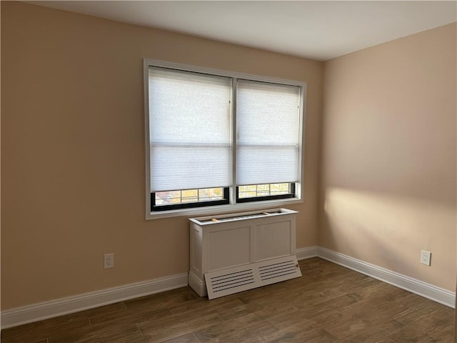 spare room featuring baseboards and dark wood-type flooring