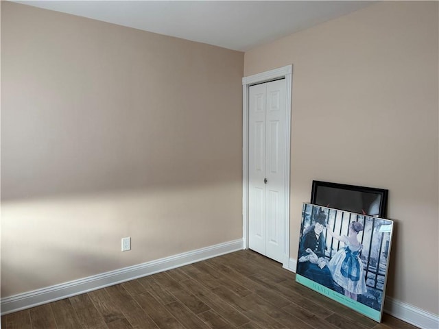 unfurnished bedroom with dark wood-style floors, baseboards, and a closet