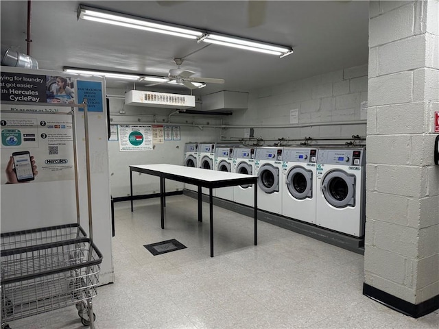 common laundry area featuring light floors, washer and clothes dryer, a ceiling fan, and concrete block wall