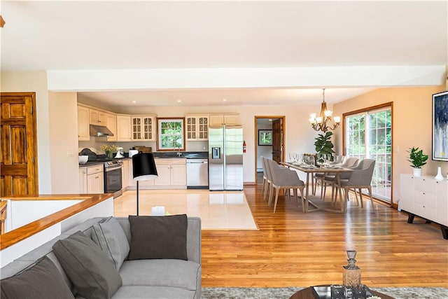 living room with an inviting chandelier, sink, and light hardwood / wood-style floors