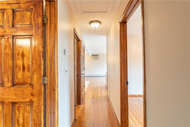 corridor with an AC wall unit and light hardwood / wood-style floors