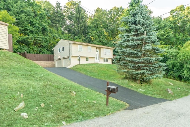 raised ranch featuring a garage and a front lawn