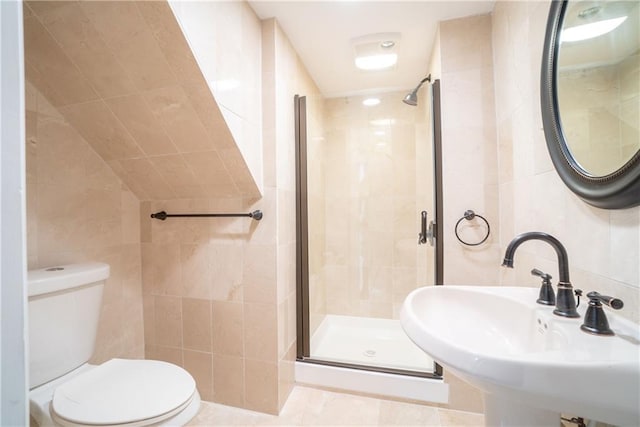 bathroom with tile patterned floors, toilet, a shower with door, tile walls, and sink