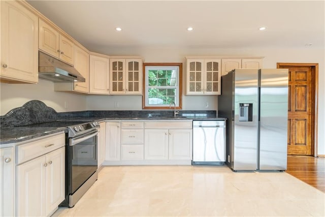 kitchen featuring dark stone countertops, sink, light hardwood / wood-style flooring, and appliances with stainless steel finishes