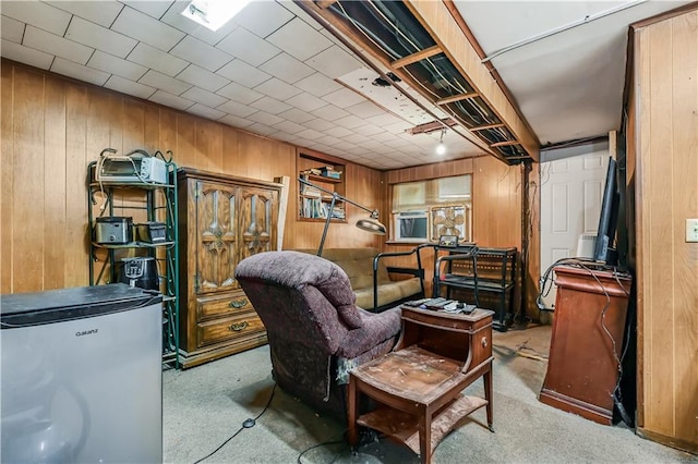 interior space featuring fridge, light colored carpet, and wooden walls