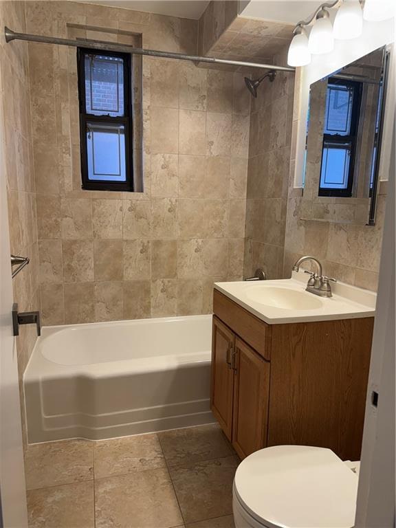 full bathroom with toilet, tile walls, tiled shower / bath, and vanity