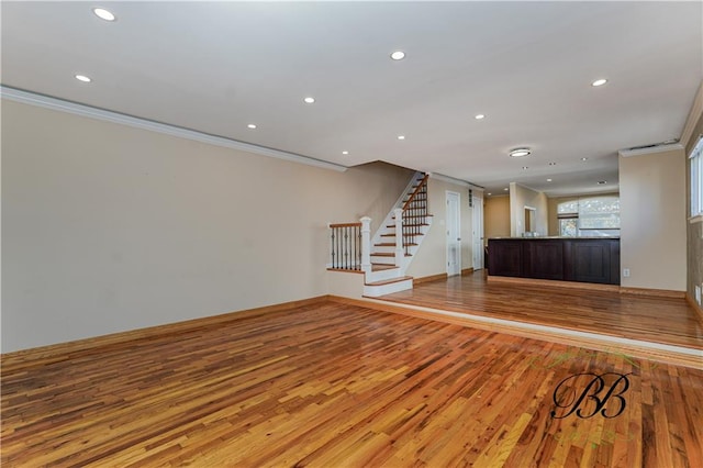 unfurnished living room with ornamental molding, stairway, light wood-style flooring, and recessed lighting