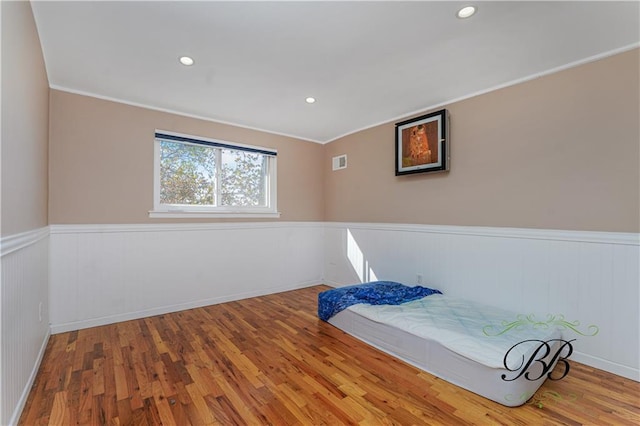 bedroom featuring visible vents, a wainscoted wall, ornamental molding, wood finished floors, and recessed lighting