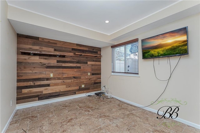 unfurnished room with recessed lighting, an accent wall, stone finish floor, wooden walls, and baseboards