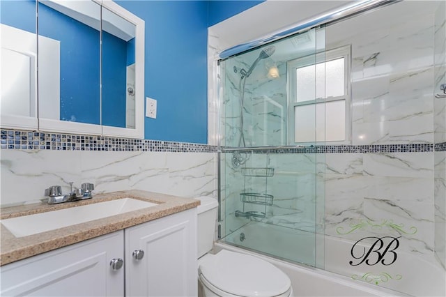 bathroom with toilet, bath / shower combo with glass door, tile walls, and vanity