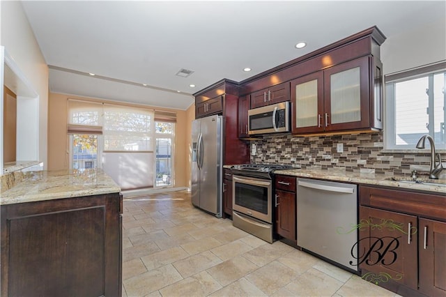 kitchen with light stone counters, tasteful backsplash, visible vents, appliances with stainless steel finishes, and a sink