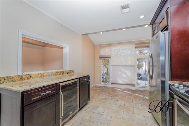 kitchen with dark brown cabinetry, visible vents, wine cooler, appliances with stainless steel finishes, and light stone countertops