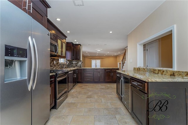 kitchen with light stone counters, stainless steel appliances, visible vents, backsplash, and a sink