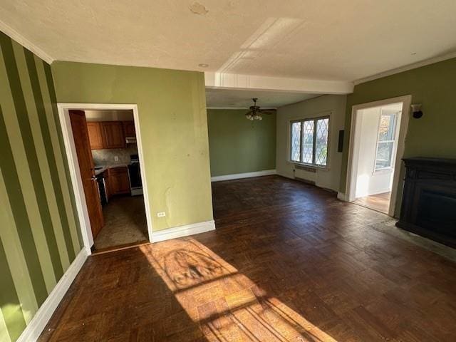 unfurnished living room with wallpapered walls, baseboards, a ceiling fan, wood finished floors, and crown molding