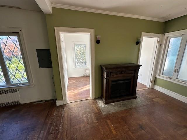 unfurnished living room with baseboards, radiator heating unit, a fireplace, and crown molding