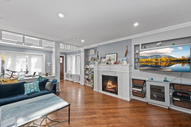 living room featuring wood-type flooring, built in shelves, crown molding, and a premium fireplace