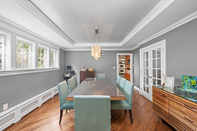 dining room featuring french doors, a baseboard heating unit, crown molding, hardwood / wood-style floors, and a tray ceiling