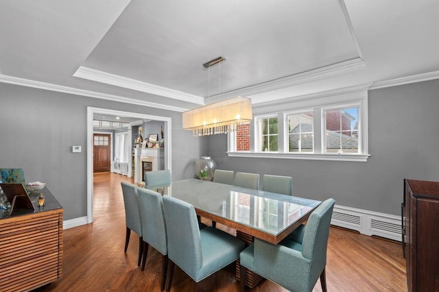 dining space featuring a raised ceiling, crown molding, and hardwood / wood-style flooring