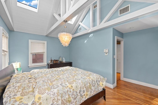 bedroom with a chandelier, light hardwood / wood-style flooring, and lofted ceiling with skylight