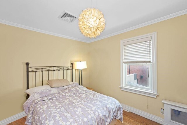 bedroom with hardwood / wood-style floors and crown molding