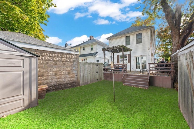 rear view of property featuring a shed, a deck, and a lawn