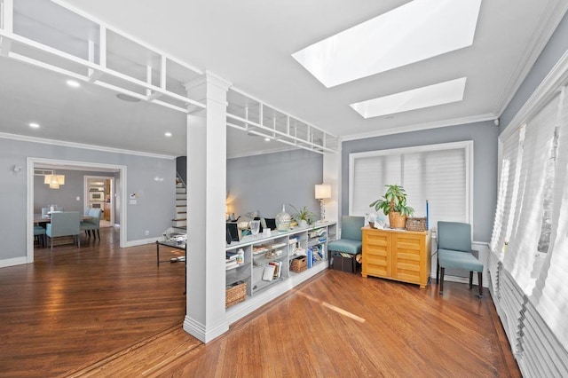 sitting room with a skylight, wood-type flooring, and ornamental molding