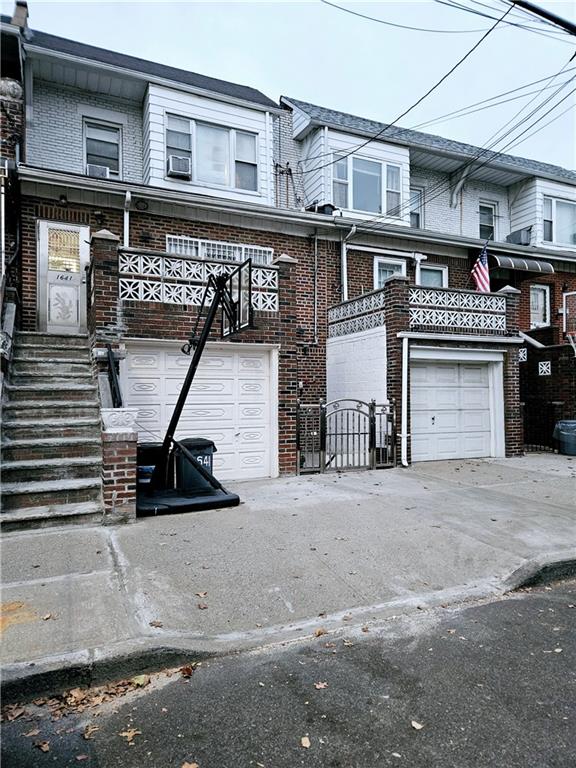 multi unit property featuring a garage, concrete driveway, and brick siding