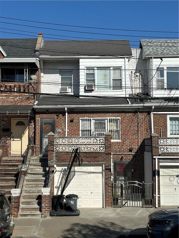 townhome / multi-family property featuring a garage, brick siding, a balcony, and a gate