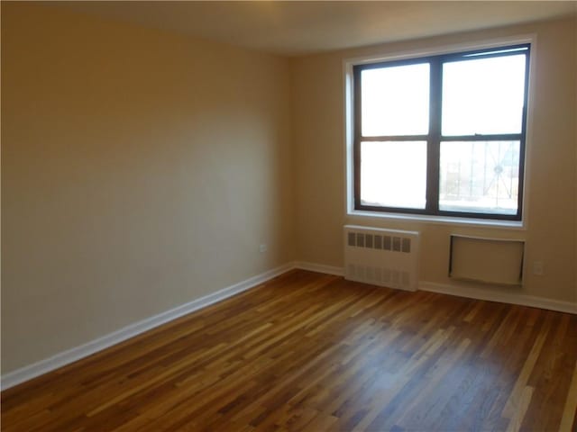 1200 E 53rd St Unit 7B, Brooklyn, NY 11234 - empty room with radiator heating unit, dark wood finished floors, and baseboards