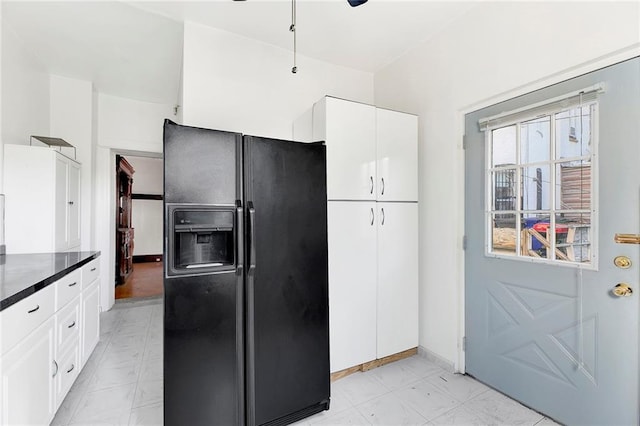 kitchen featuring black fridge with ice dispenser and white cabinetry