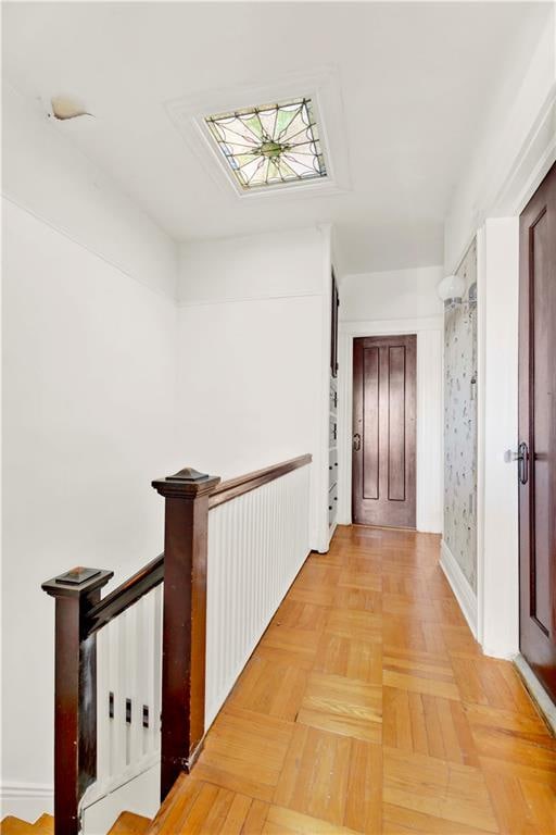 hall featuring an upstairs landing and baseboards