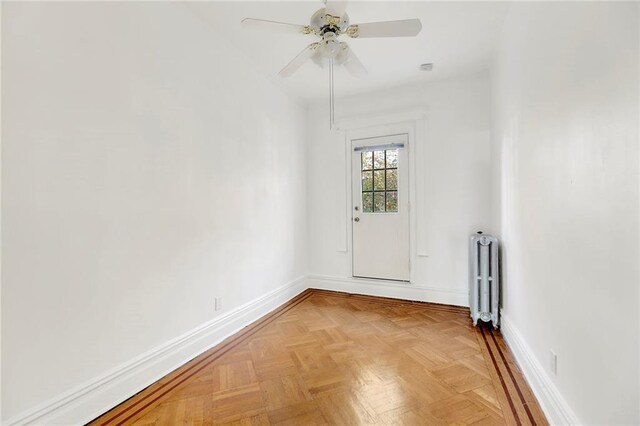 spare room with light parquet floors, radiator, and ceiling fan