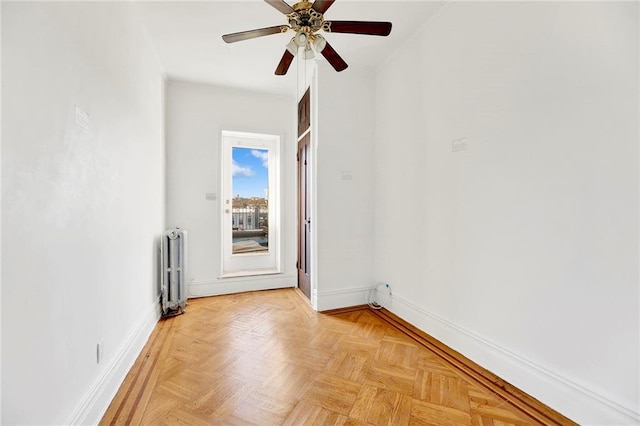 spare room with ceiling fan, radiator heating unit, and light parquet flooring