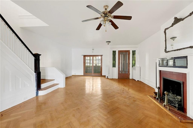 unfurnished living room featuring ceiling fan, a fireplace, and parquet flooring