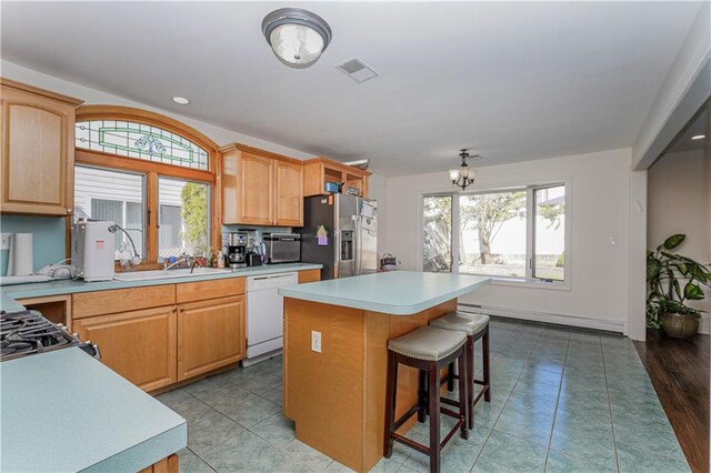 kitchen featuring a center island, baseboard heating, a breakfast bar, light wood-type flooring, and appliances with stainless steel finishes