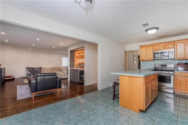 kitchen with wood-type flooring, a kitchen island, appliances with stainless steel finishes, a baseboard radiator, and a breakfast bar area