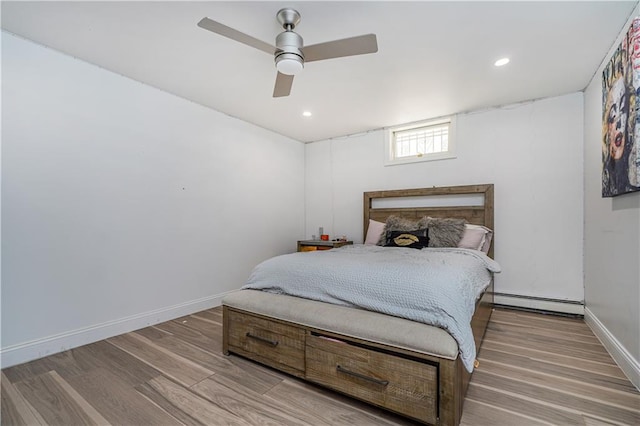 bedroom with baseboard heating, hardwood / wood-style flooring, and ceiling fan