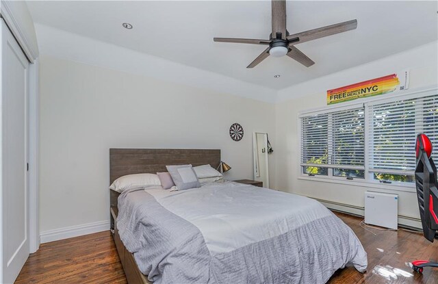 bedroom featuring a baseboard radiator, dark hardwood / wood-style flooring, ceiling fan, and a closet