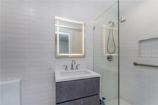 bathroom featuring a shower with shower door, vanity, and tile walls