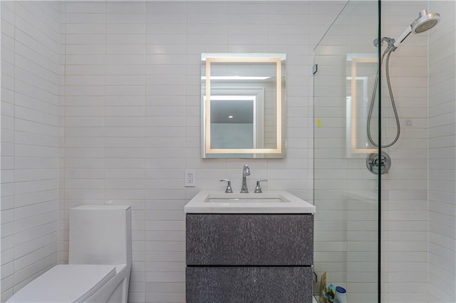 bathroom featuring vanity, toilet, a tile shower, and tile walls