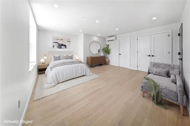 bedroom featuring light hardwood / wood-style flooring and an AC wall unit