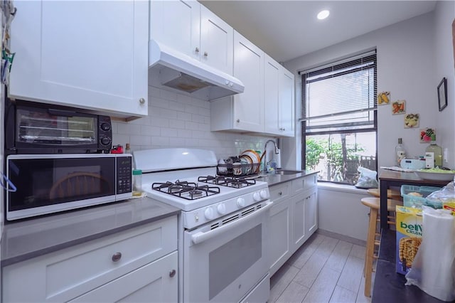 543 49th St, Brooklyn, NY 11220 - kitchen featuring a sink, under cabinet range hood, white cabinets, white gas range oven, and backsplash