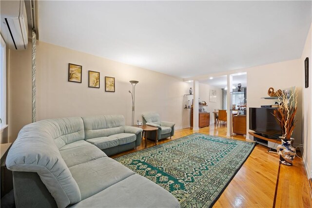 living room featuring a wall mounted air conditioner and hardwood / wood-style floors