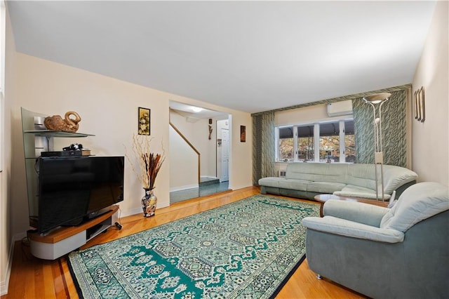 living room featuring wood-type flooring and an AC wall unit