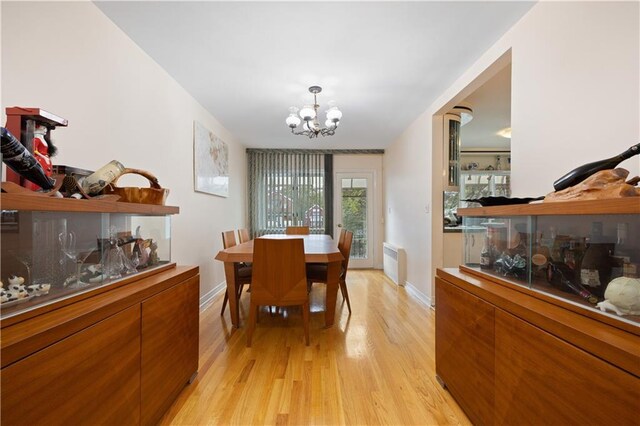 dining room with a chandelier, radiator, and light hardwood / wood-style floors