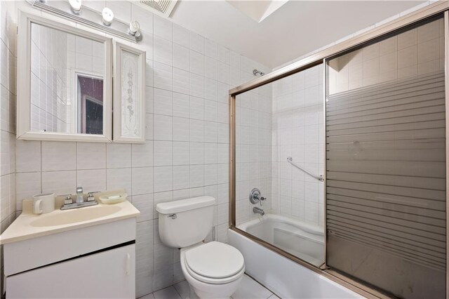 full bathroom featuring tile walls, vanity, shower / bath combination with glass door, and toilet