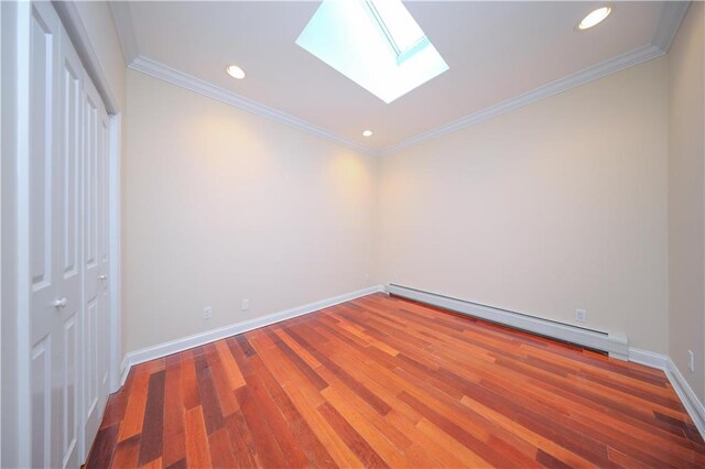 spare room with a baseboard radiator, wood-type flooring, ornamental molding, and a skylight